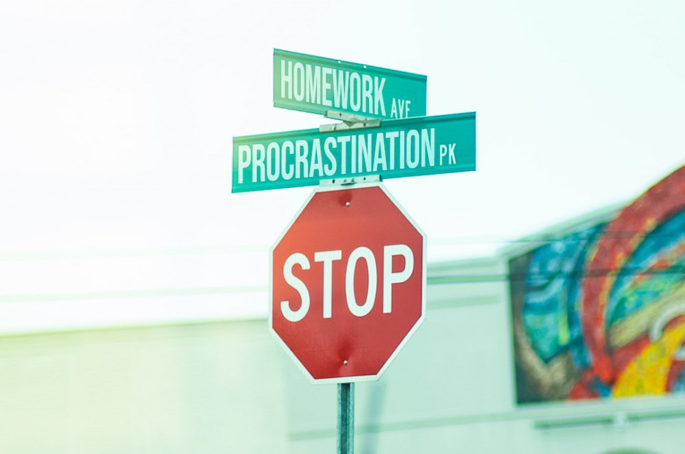 Picture of a stop sign with cross streets Homework Avenue and Procrastination Park