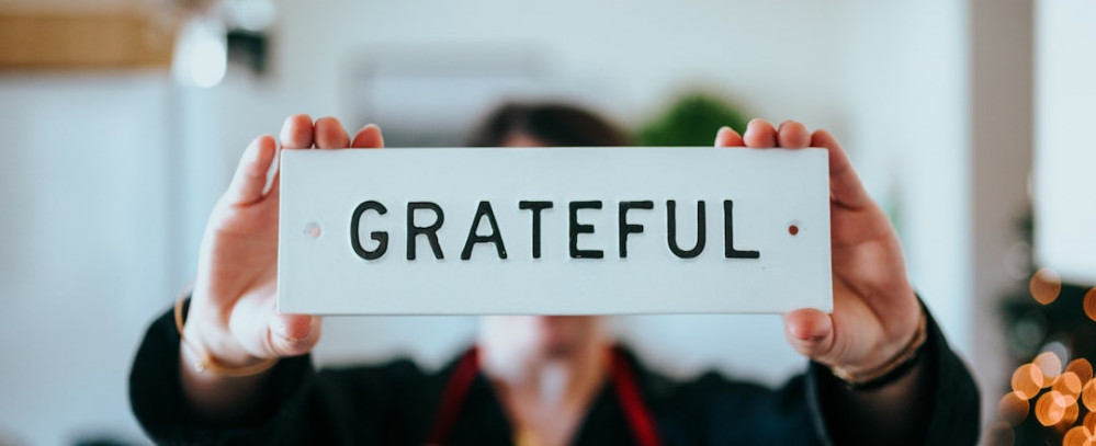 A person holding a sign that displays the word grateful