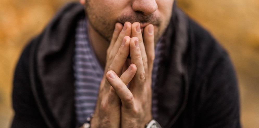 A man holding his hands together while thinking