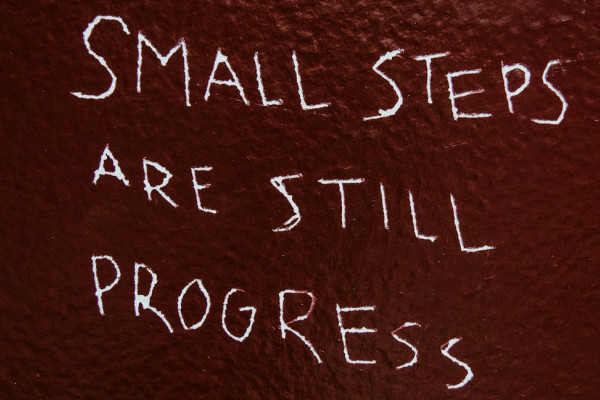 A reddish brown box displaying the words "Small steps are still progress."